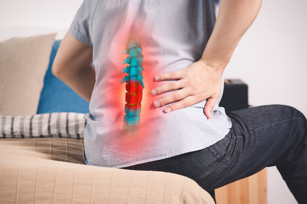 Pain in the spine, a man with backache at home, injury in the lower back