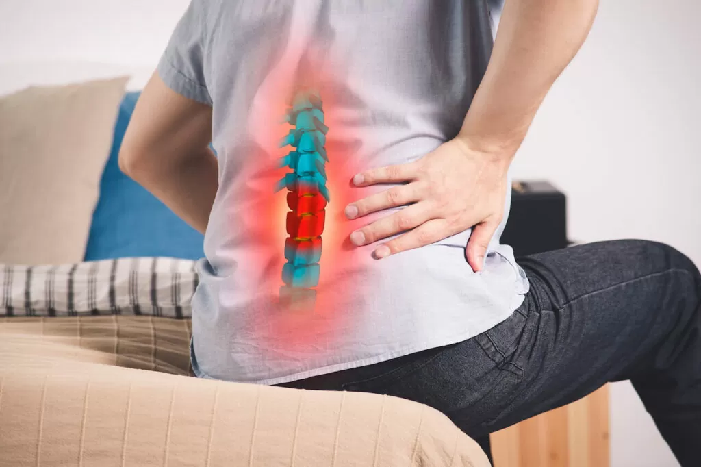 Pain in the spine, a man with backache at home, injury in the lower back